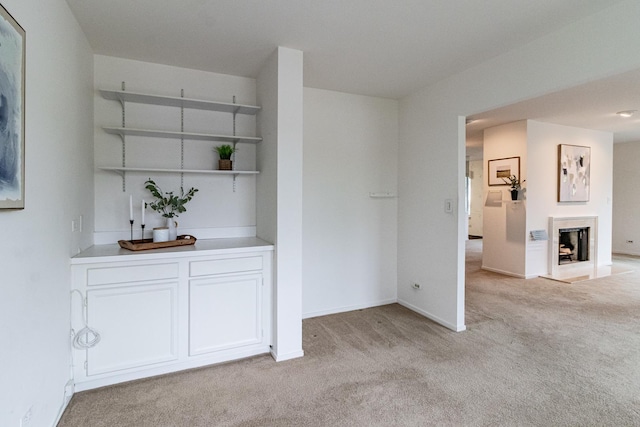 interior space with a fireplace, baseboards, and light carpet