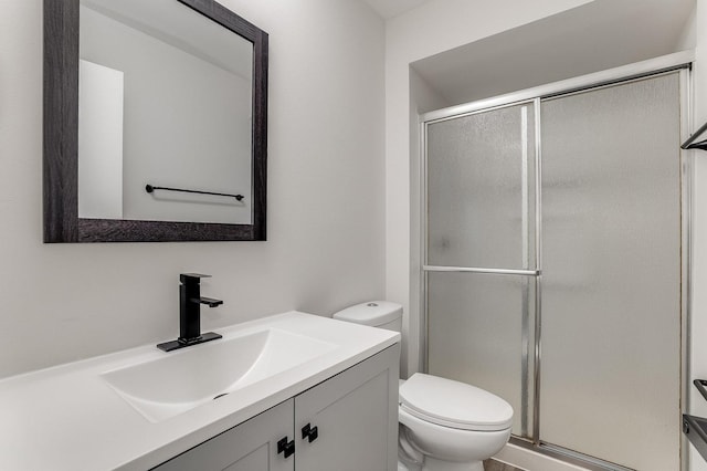 full bathroom featuring a stall shower, toilet, and vanity