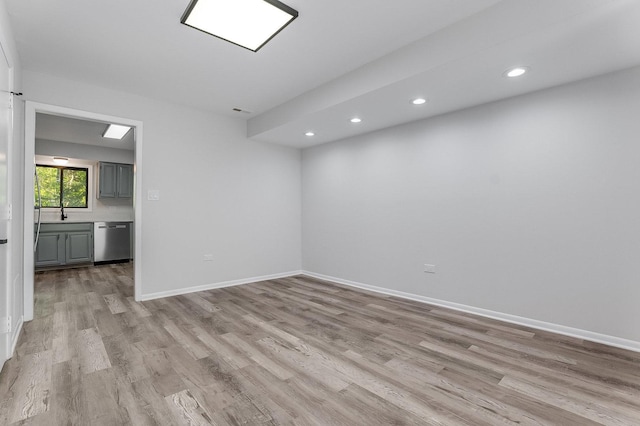 spare room featuring light wood-type flooring, recessed lighting, baseboards, and a sink