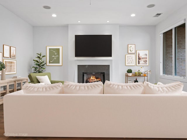 living room featuring a lit fireplace, dark wood-style flooring, and recessed lighting