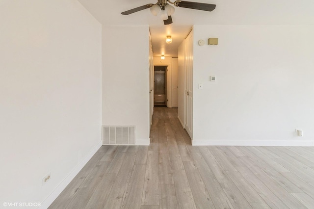spare room with light wood-type flooring, ceiling fan, and baseboards