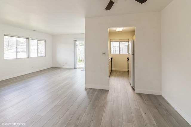 empty room with ceiling fan, wood finished floors, and healthy amount of natural light