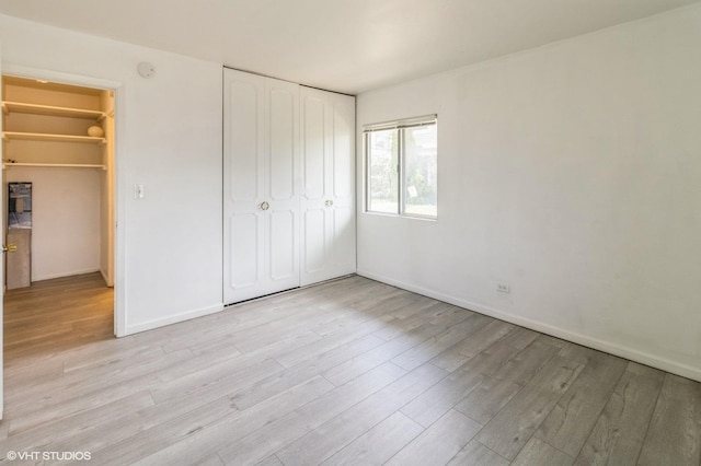 unfurnished bedroom with a closet, light wood-style floors, and baseboards