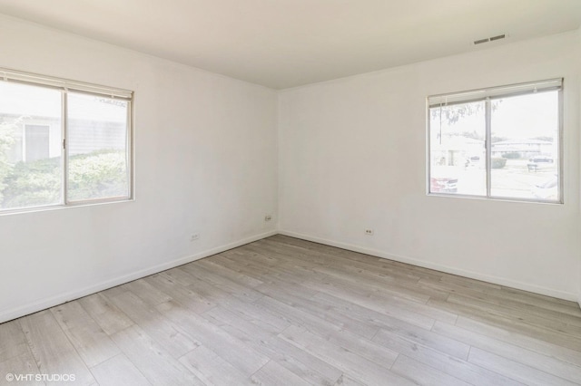 spare room with light wood-style floors, healthy amount of natural light, and baseboards