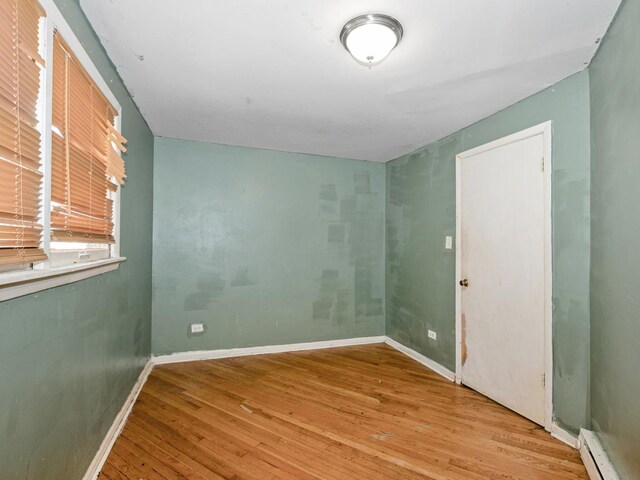 2720 E 76th Pl, Chicago, IL 60649 - spare room featuring wood finished floors, a baseboard heating unit, and baseboards