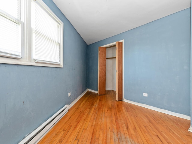 2720 E 76th Pl, Chicago, IL 60649 - unfurnished bedroom with a baseboard heating unit, hardwood / wood-style floors, baseboards, and vaulted ceiling