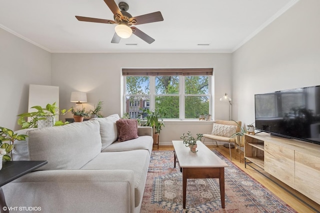 living area featuring crown molding, light wood-style flooring, and ceiling fan