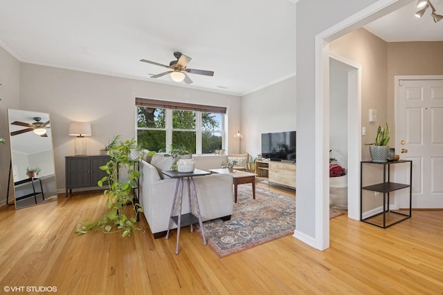 living room with ceiling fan, crown molding, baseboards, and wood finished floors