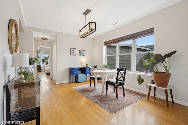 dining room with crown molding, plenty of natural light, light wood-style flooring, and baseboards