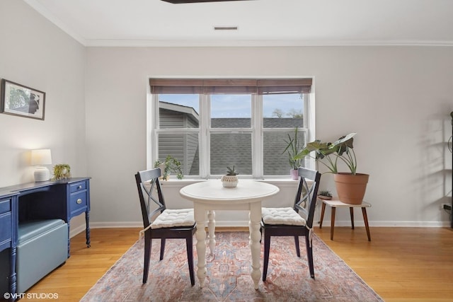 dining area with baseboards, crown molding, visible vents, and light wood-type flooring