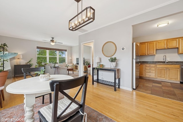 dining space featuring light wood-type flooring, baseboards, a ceiling fan, and ornamental molding