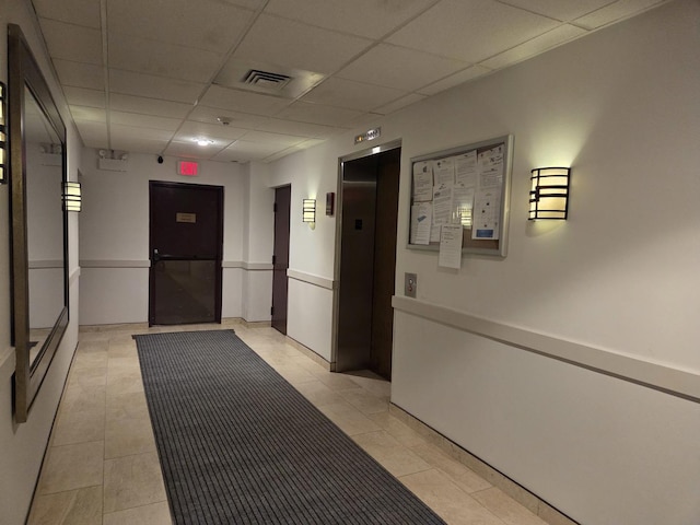 corridor with visible vents, elevator, light tile patterned flooring, and a paneled ceiling