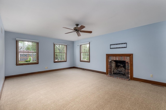 unfurnished living room with light colored carpet, baseboards, a fireplace, and a ceiling fan