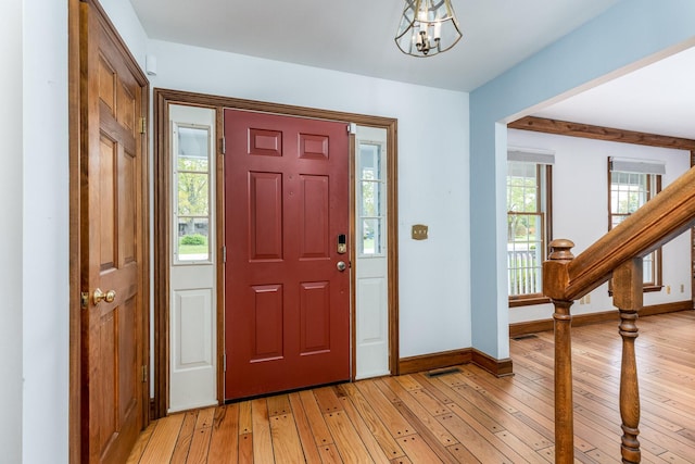 foyer with an inviting chandelier, stairs, baseboards, and light wood-type flooring