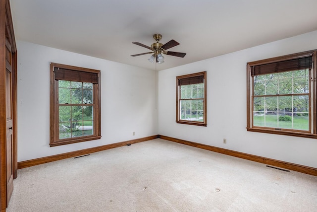 unfurnished room featuring carpet flooring, a wealth of natural light, visible vents, and baseboards