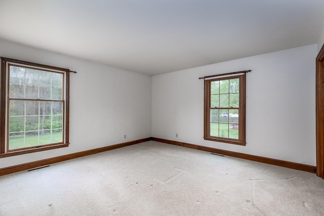 spare room featuring light colored carpet, visible vents, and baseboards