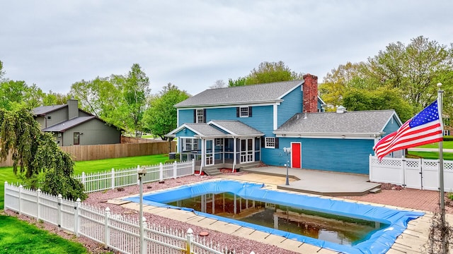 view of swimming pool featuring a sunroom, a lawn, a wooden deck, and a fenced backyard
