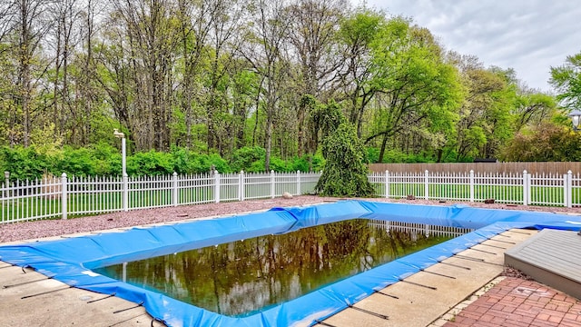 view of pool with fence, a fenced in pool, and a view of trees