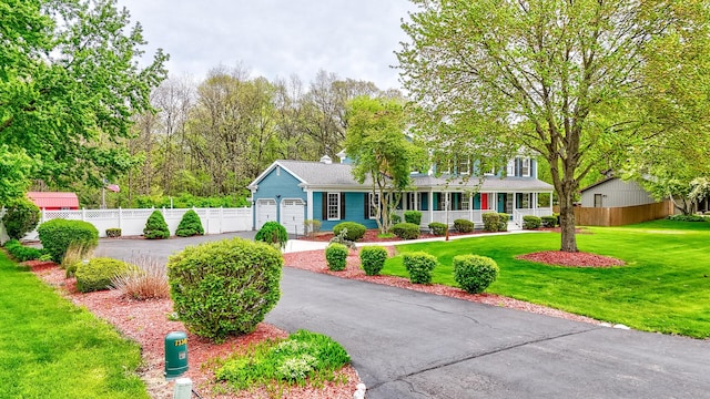 ranch-style house featuring an attached garage, fence, a front yard, a porch, and driveway