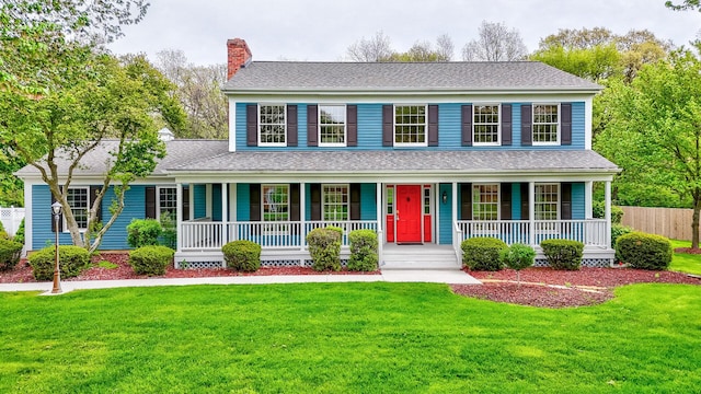 view of front of home with a chimney, a front lawn, and covered porch