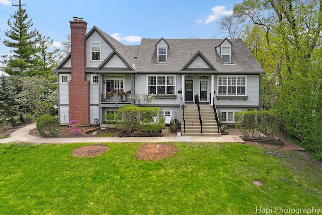 623 Broadway St, Libertyville, IL 60048 - new england style home featuring a chimney, a front yard, stairway, and covered porch