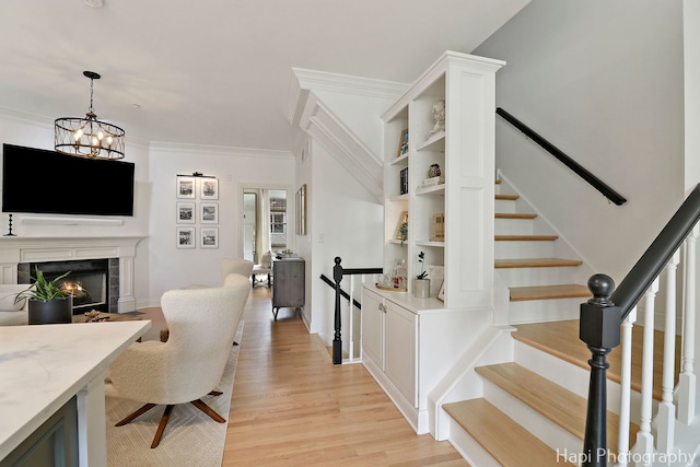 623 Broadway St, Libertyville, IL 60048 - staircase featuring crown molding, wood finished floors, a fireplace, baseboards, and a notable chandelier