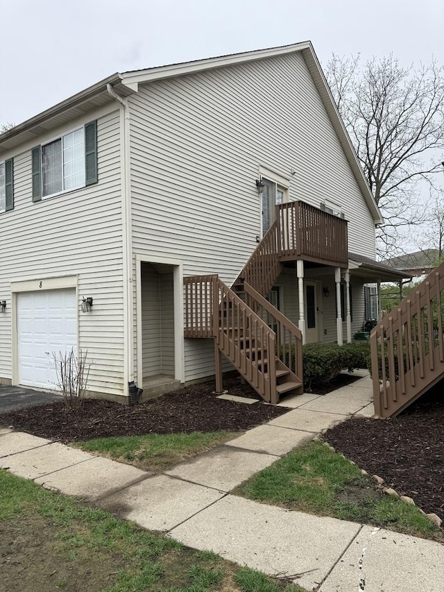 view of side of property featuring stairs, an attached garage, and a deck