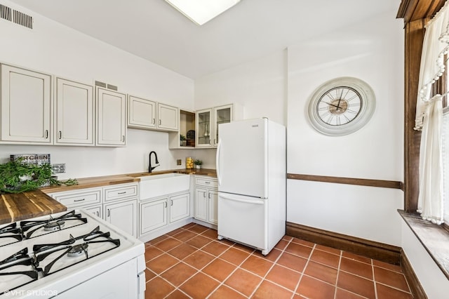 2137 W Cortez St Unit 2, Chicago, IL 60622 - kitchen featuring white appliances, a sink, wood counters, glass insert cabinets, and dark tile patterned floors
