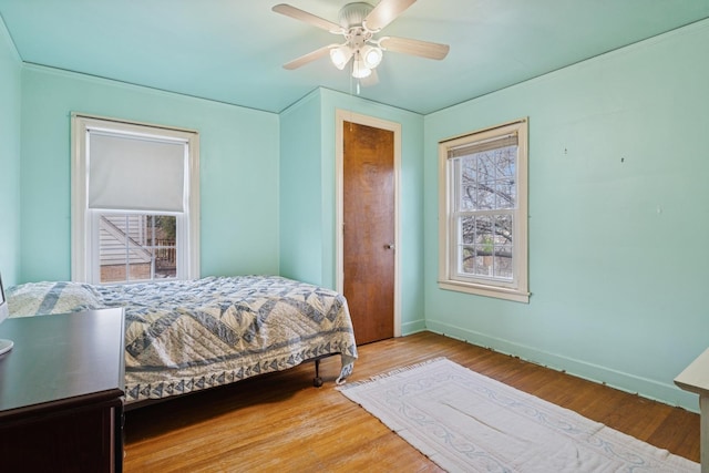 bedroom featuring baseboards, multiple windows, and wood finished floors