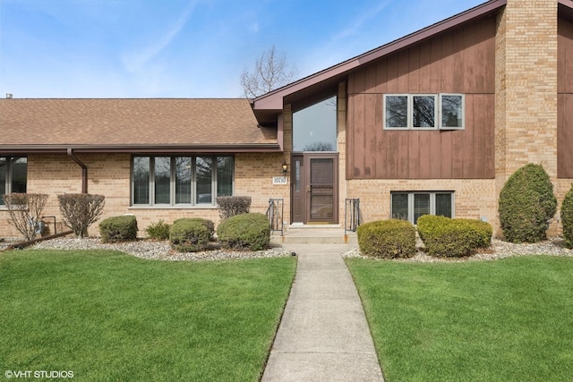 tri-level home with brick siding, a shingled roof, and a front yard