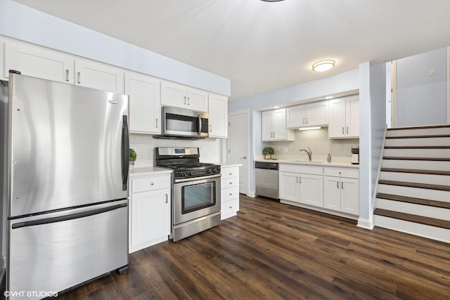 kitchen with light countertops, appliances with stainless steel finishes, white cabinets, and dark wood-style floors