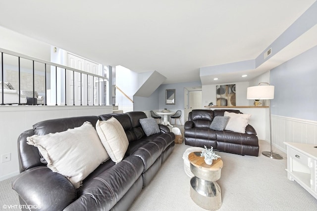 carpeted living room featuring visible vents, wainscoting, and stairway