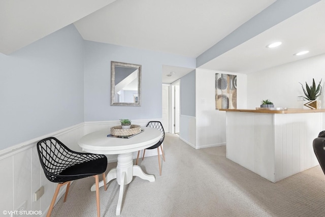 dining area featuring bar, recessed lighting, light carpet, and a wainscoted wall