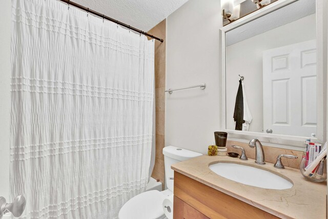 full bathroom featuring toilet, a textured ceiling, and vanity