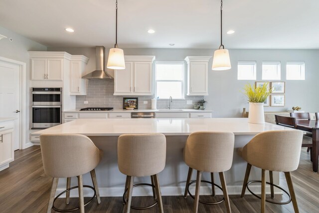 302 Links Dr, Addison, IL 60101 - kitchen featuring wall chimney range hood, a sink, stainless steel appliances, tasteful backsplash, and white cabinets