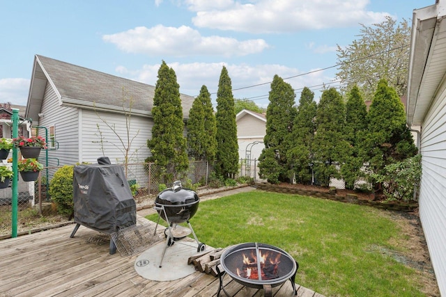 view of yard featuring an outdoor fire pit, a deck, and fence
