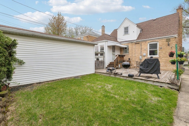back of house featuring a lawn, a deck, and roof with shingles