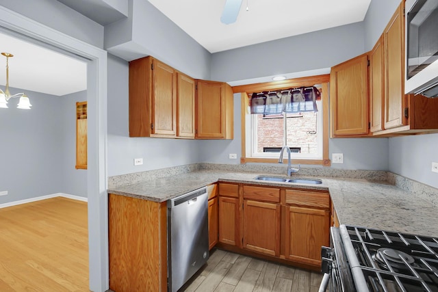 kitchen featuring appliances with stainless steel finishes, a sink, light wood-type flooring, and brown cabinetry