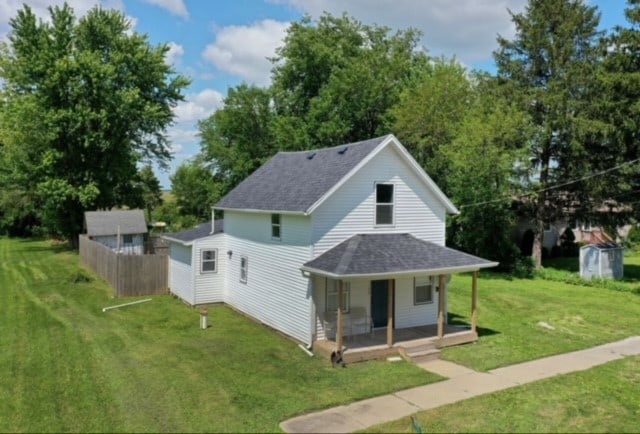 back of house featuring a lawn, a porch, a shingled roof, and fence