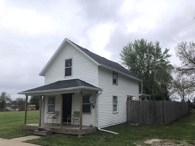 exterior space featuring a porch, fence, and a lawn