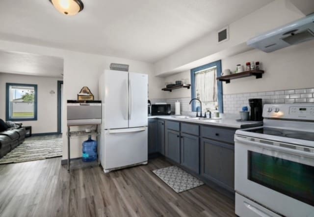 kitchen featuring open shelves, plenty of natural light, a sink, and white appliances