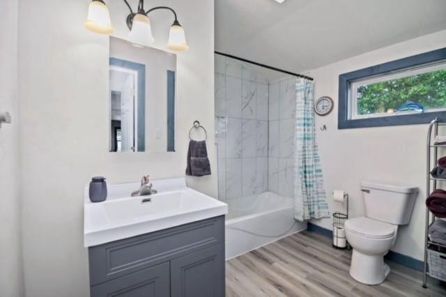bathroom with vanity, toilet, shower / tub combo, and wood finished floors