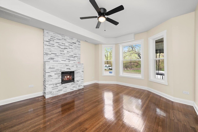 unfurnished living room with baseboards, a tile fireplace, visible vents, and hardwood / wood-style flooring