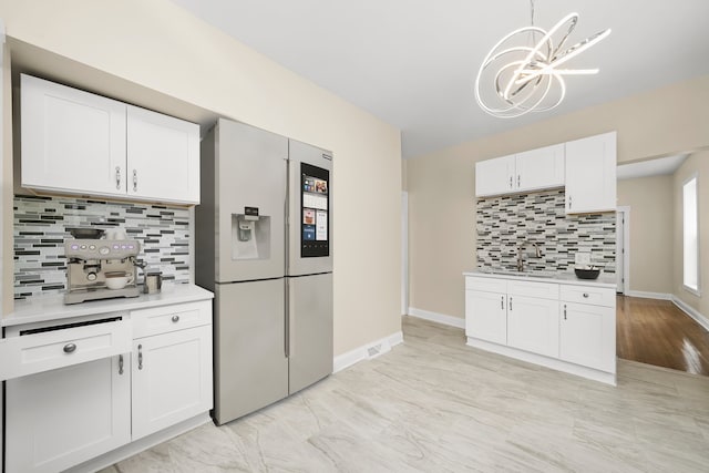 kitchen with an inviting chandelier, white fridge with ice dispenser, white cabinetry, light countertops, and decorative backsplash