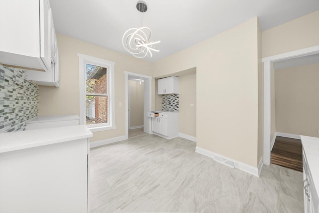 unfurnished dining area featuring visible vents, baseboards, and a notable chandelier