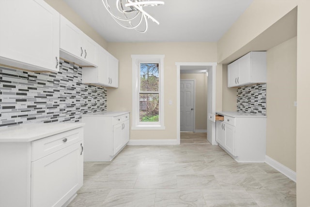 kitchen featuring white cabinets, a notable chandelier, light countertops, marble finish floor, and decorative backsplash