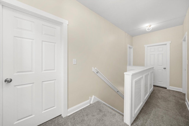 corridor with carpet floors, baseboards, and an upstairs landing