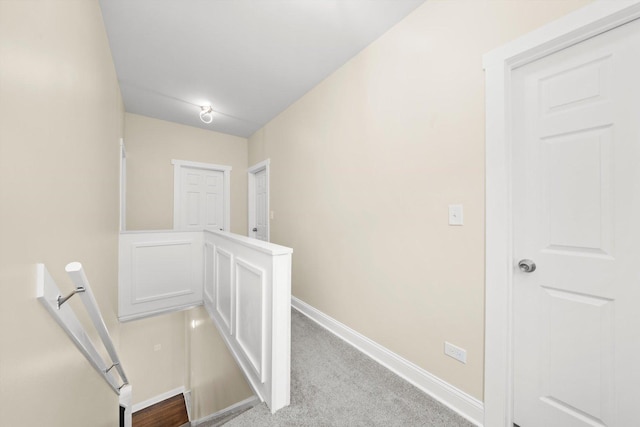 corridor featuring carpet floors, baseboards, and an upstairs landing