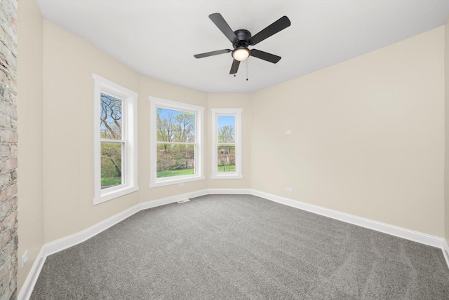 spare room with baseboards, dark carpet, and visible vents