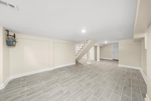 finished basement with stairway, baseboards, visible vents, and recessed lighting